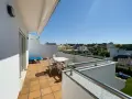 Słoneczny balkon z meblami i widokiem na domki. Idealne miejsce na poranną kawę i planowanie dnia.