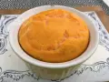 Un délicieux flan de carottes, doré et moelleux, servi dans un ramequin blanc sur une assiette décorée.