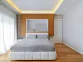 Camera da letto con letto bianco, lenzuola grigie e un moderno controsoffitto con illuminazione a LED.