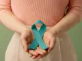 Dłonie trzymają turkusową wstążkę, symbolizującą wsparcie dla kobiet z PCOS. Dowiedz się, pcos co to.