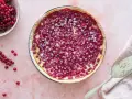 Saftiger Johannisbeerkuchen mit Schmand in einer Springform, bestäubt mit Puderzucker. Daneben eine Schale voller roter Johannisbeeren.