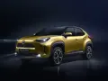 Złoty Toyota Yaris Cross Hybrid z włączonymi światłami na ciemnym tle.