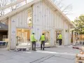 Construction d'une maison écologique passive en bois. Des ouvriers en gilets de sécurité supervisent le chantier.