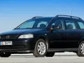 Schwarzer Opel Astra Kombi, alt, mit Dachreling und Kennzeichen GG SN 771, parkt auf einem Parkdeck vor blauem Himmel.