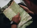 Un randonneur consulte une carte IGN des plateaux du Vercors, pointant un chemin sur le terrain.