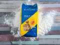 Opakowanie mąki Bezgluten Multi Mix, rozsypana mąka na drewnianym tle. To najzdrowsza mąka bezglutenowa do Twoich wypieków.