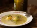 Aromatyczna keto zupa ogórkowa z ziemniakami i koperkiem, podana na talerzu z kwiatowym wzorem. Obok stoi słoik ogórków.