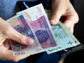 Dłonie trzymają polskie banknoty 20 zł i 100 zł. Wkrótce może pojawić się ryczałt energetyczny.