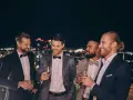 Eleganccy panowie w garniturach i muszkach, pijący drinki na tarasie. Idealny przykład, jak się ubrać na poprawiny.