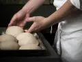 Mani esperte sistemano impasti per pizza, un mestiere che fa riflettere su quanto guadagna un pizzaiolo al mese.