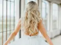 Długie, falowane blond włosy ozdobione złotą spinką. Fryzura w stylu lat 20. idealna na ślub.