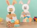 Zwei süße Osterhasen halten Karotten. Kinder haben diese tollen Osterdeko zum Thema Osternest basteln Kinder selbst gemacht.