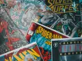Stos komiksów z postaciami takimi jak Spider-Man, Batman i Silver Surfer. Czy komiks to książka? To zależy od tego, jak na to spojrzeć!