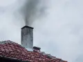 Dym wydobywający się z komina na tle pochmurnego nieba.
