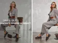 Kobieta w szarym garniturze z szerokimi nogawkami prezentuje, jakie buty do szerokich eleganckich spodni wybrać – czarne lakierowane mokasyny na grubej podeszwie.