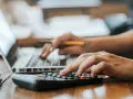 Hände bedienen Laptop und Taschenrechner. So lässt sich die Kaution in Raten zahlen und die Finanzen im Blick behalten.