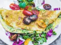 Złocisty omlet z cukinią, podany z kolorową sałatką i pomidorkami koktajlowymi. Pyszne i zdrowe śniadanie.