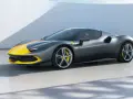 Szary Ferrari 296 GTB z żółtymi pasami na masce i dachu, stojący na betonowej posadzce.