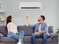 Pareja ajustando el aire acondicionado para encontrar la temperatura ideal y ahorrar energía.