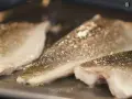 Filetes de lubina a la donostiarra dorándose en una sartén.