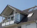 Dachgaube mit Balkon und Solarpaneelen. Informieren Sie sich über Dachgaube Kosten für Ihr Zuhause.