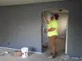 Un peintre en bâtiment applique de la peinture sur un mur. Pour savoir comment reconnaître un mur porteur, observez la structure et l'épaisseur.