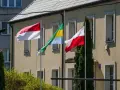 Trzy flagi powiewają przed budynkiem: biało-czerwona flaga Polski, flaga Monako (identyczna jak Indonezji) i flaga Gabonu.