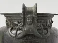 Détail du vase de Vix : une figure féminine aux longs cheveux, entourée de serpents, orne ce chef-d'œuvre antique.