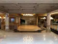 Eleganckie lobby hotelowe z fortepianem, recepcją i dwoma pracownikami.