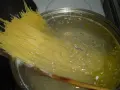 Długi makaron spaghetti gotuje się w bulgoczącej wodzie. Czas, **ile gotować makaron**, zależy od jego grubości.