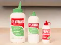Tre flaconi di colla Vinavil, un adesivo universale pva glue cos'è, in diverse misure, con tappi verdi e rossi.
