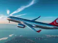 Samolot Turkish Airlines leci nad miastem i morzem przy zachodzącym słońcu.