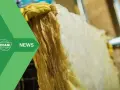 Mano guantata che tiene un pannello di lana di vetro, materiale isolante per l'edilizia.