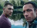 Dwóch mężczyzn patrzy w obiektyw na tle jeziora. Scena z jednego z popularnych polskich seriali.