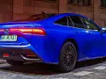 Niebieska Toyota Mirai z podświetlonymi światłami tylnymi stoi na brukowanej ulicy nocą.
