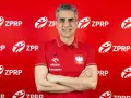 Uśmiechnięty mężczyzna, były trener piłkarzy ręcznych, w czerwonej koszulce z godłem Polski i logo ZPRP.