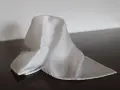 Un fazzoletto bianco di seta, drappeggiato su un tavolo scuro. Il suo significato è legato alla purezza e all'eleganza.