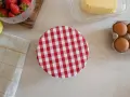 Préparation d'une charlotte alimentaire : fraises, citron, beurre, œufs et un couvercle à carreaux rouges et blancs.