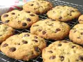 Un montón de galletas con pepitas de chocolate recién horneadas, doradas y deliciosas, enfriándose en una rejilla.