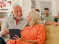 Uśmiechnięci seniorzy przeglądają tablet, obok nich logo "Karta Seniora Ogólnopolska".