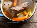 Brodo di carne ricetta della nonna in pentola: carne, carote, sedano e cipolla con chiodi di garofano. Profumo di casa.