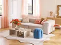 Ein Wohnzimmer mit beigem Sofa, orangefarbenen Tulpen und Korbmöbeln. Die sanften Pfirsichtöne der Vorhänge und Kissen zeigen, welche Farben passen zusammen.
