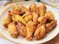 Alitas de pollo doradas y crujientes en un plato blanco.