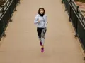 Kvinna springer på bro i Hoka One One Bondi 8-skor.