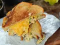 Ein köstlicher Tuna Melt mit geschmolzenem Käse, serviert mit Gurken und Chips.