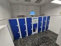 Blue and white numbered luggage lockers with a digital screen and instructions.