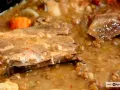 Guiso de lentejas con costillas, zanahoria y trozos de carne en un caldo espeso.