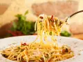 Widok z bliska na widelec z porcją spaghetti, posypane parmezanem i ziołami. Idealne jakie przyprawy do spaghetti!
