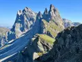 Majestätische Felszinnen ragen in den blauen Himmel. Eine **Seceda Wanderung** führt durch grüne Almwiesen und felsiges Gelände.