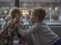 Bambina con disturbo della comunicazione sociale si nasconde, mentre un bambino le parla con un sorriso.
